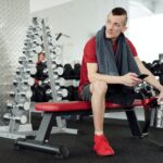 Man in Red Shirt and Black Shorts Sitting on Red and Black Chair