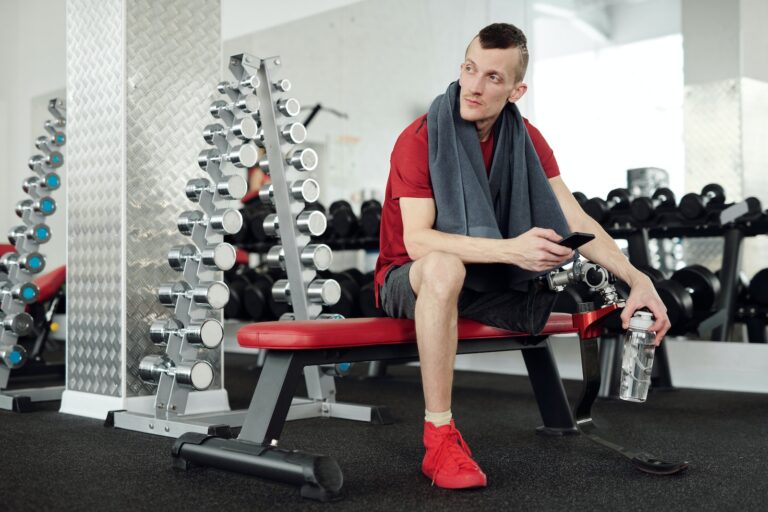 Man in Red Shirt and Black Shorts Sitting on Red and Black Chair