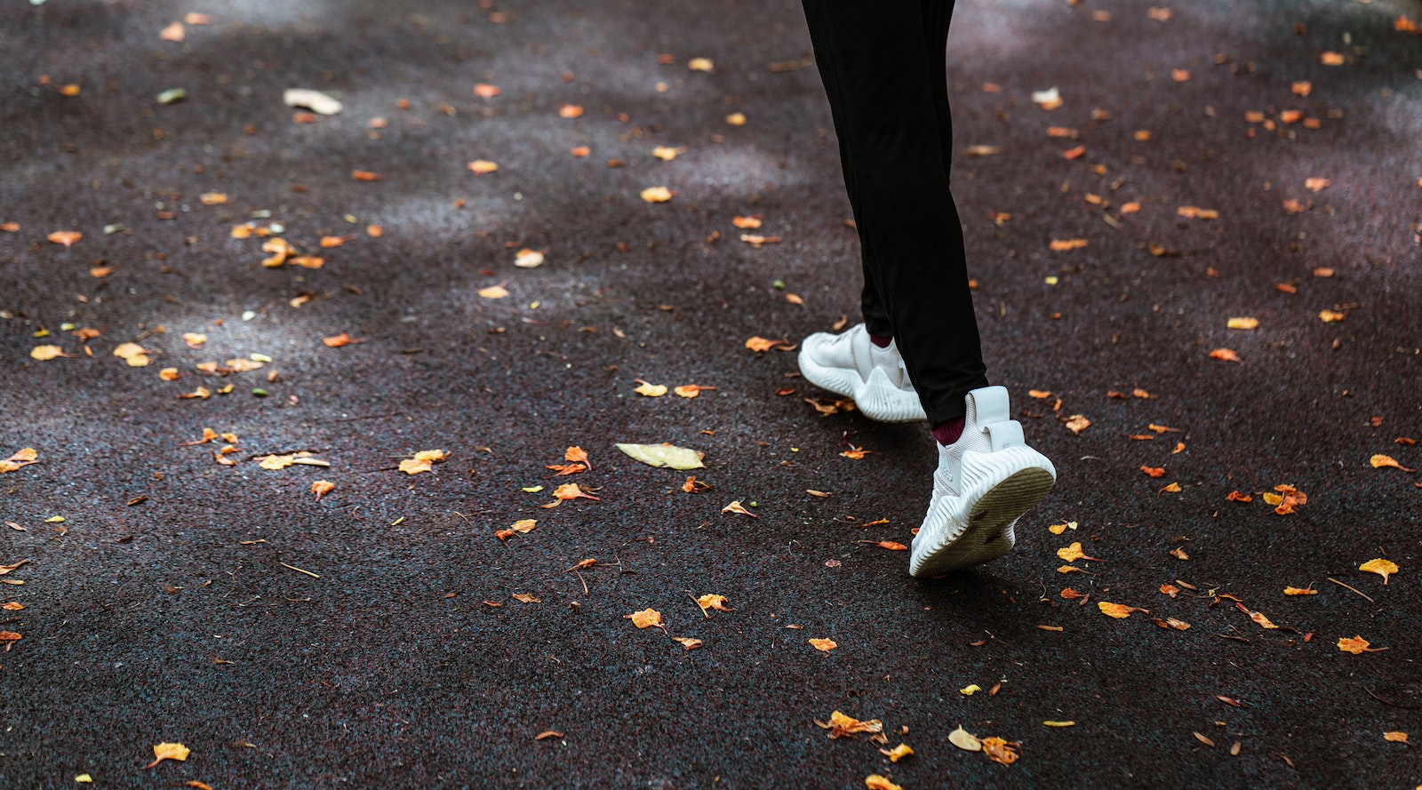 Faceless person running on dark pavement