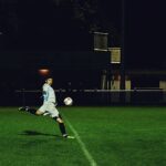 Person Kicks Soccer Ball in Field