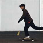 man in black pants and brown jacket riding skateboard